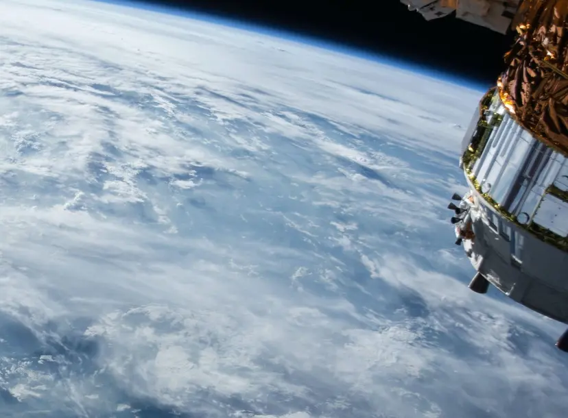 The earth from a distance, with a spaceship satelite coming towards it 