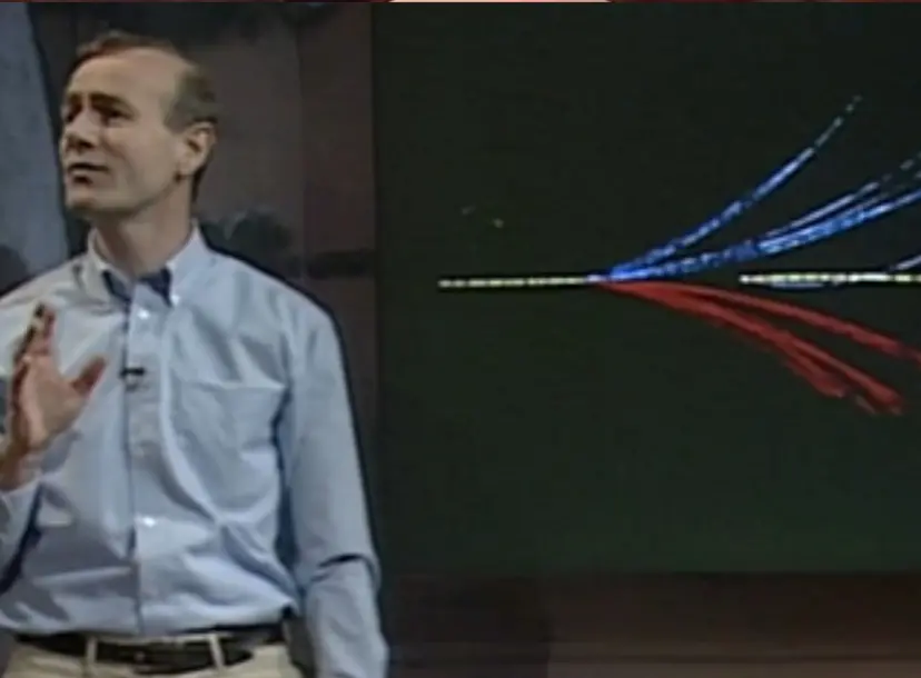 Frank Close speaking in front of a graphic of different coloured lines, in the Ri Theatre