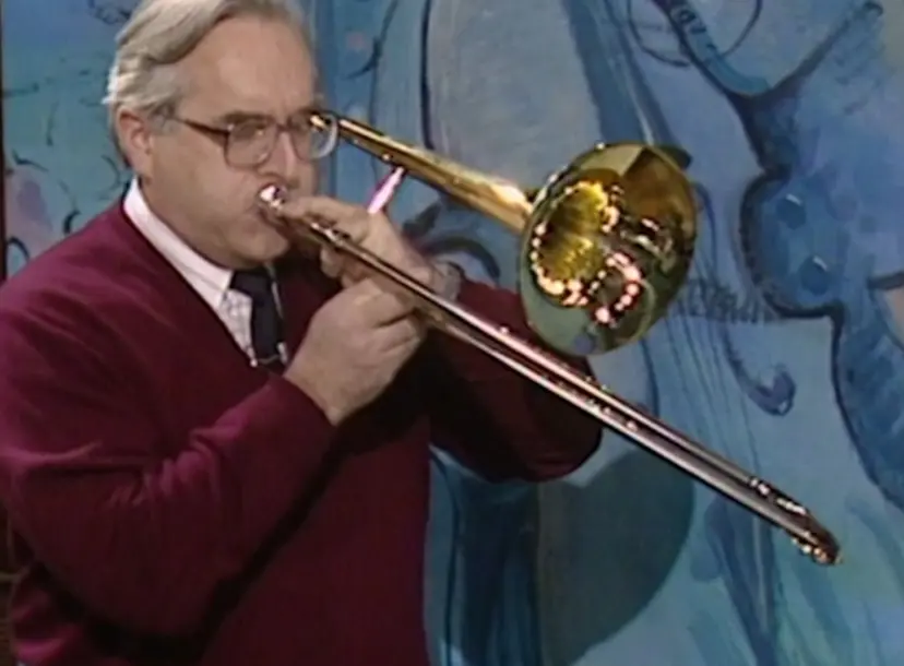A man with glasses playing a trombone