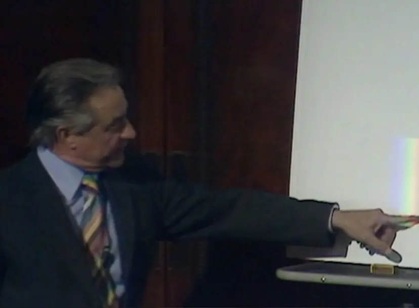 George Porter pointing at a rainbow beam of light on a white screen