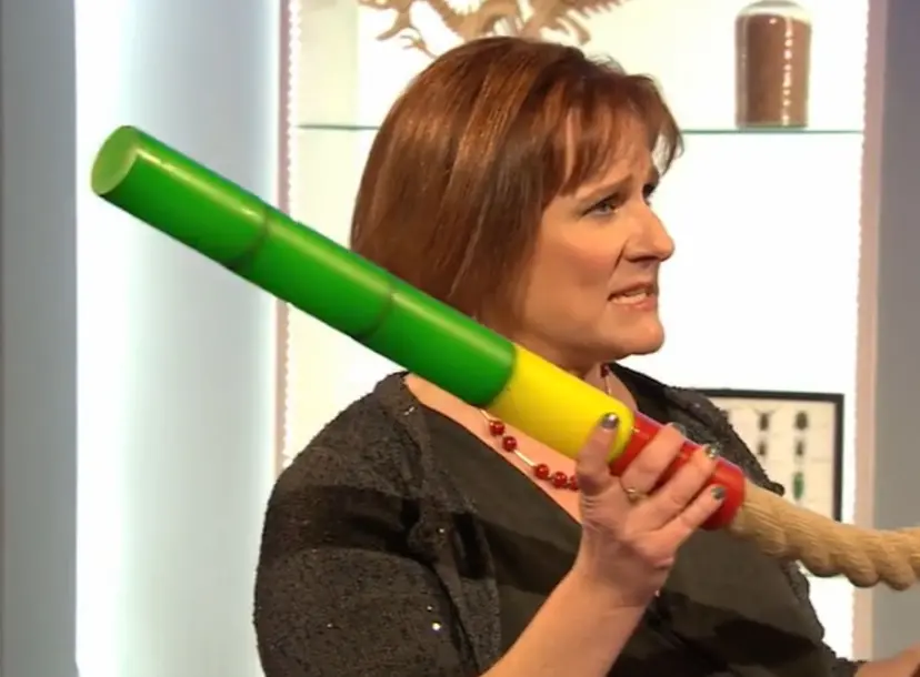 Alison Woollard holding a length of rope, which has a rainbow coloured nozzle attached to it 