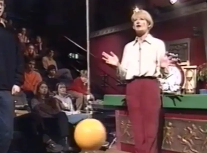 Nancy Rothwell stands between two hanging wires with coloured balls on the ends 