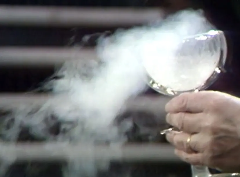 A glass goblet with smoke billowing out from it 