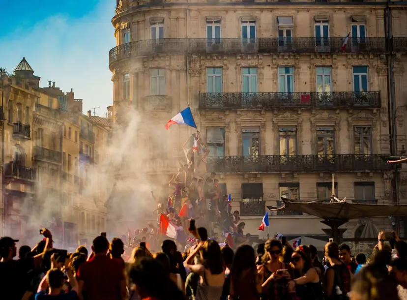 People gathered on a statue waving French flags 