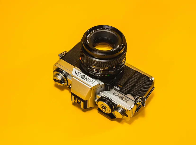 A film camera on a yellow flat backdrop