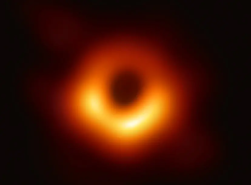 The 2019 Event Horizon Telescope black hole image. Against a dark background, a hollow red and orange circle stands out