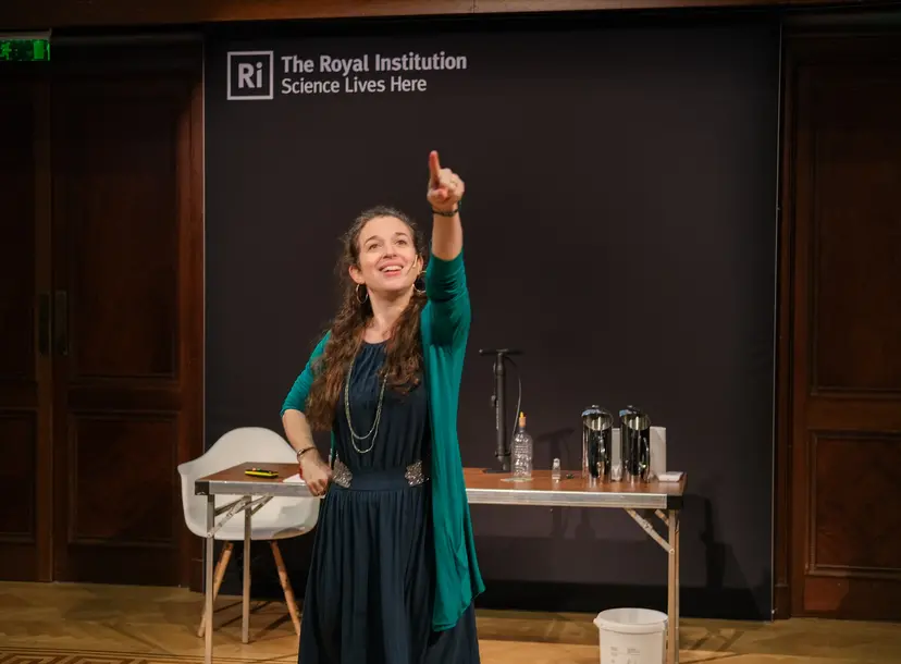 A woman stood pointing upwards in the royal institution theatre