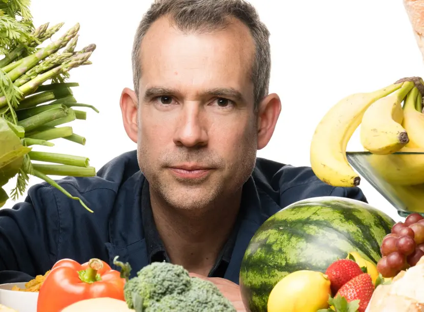 Chris looks into the camera surrounded by different types of food
