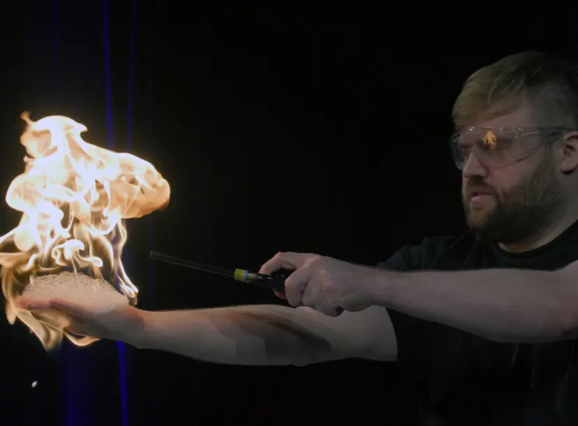 A science demonstrator at the Ri holding a flame