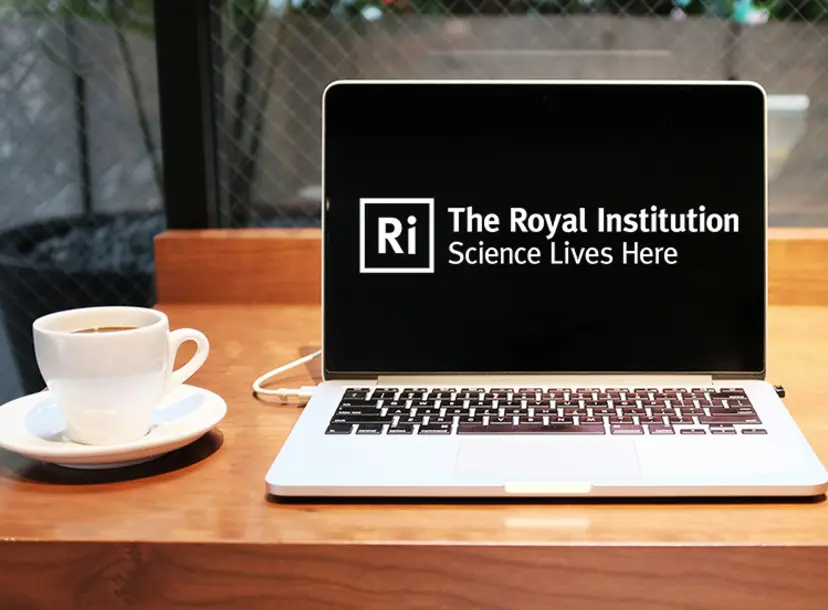 A laptop on a table showing the Ri logo
