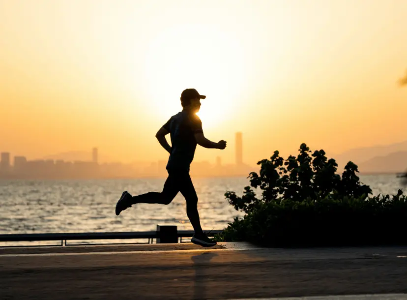 Silhouette of a man running on the beach at sunset.