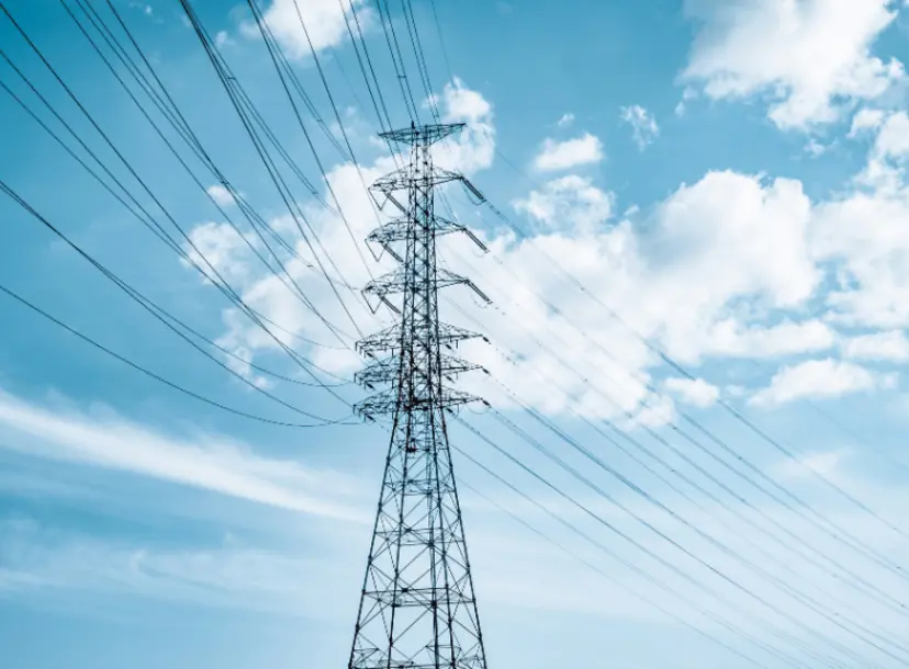 Electric tower under blue sky and white clouds during daytime.