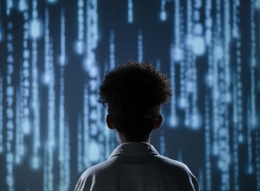 The back of a young person's head as they look at streams of data