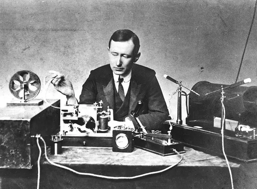 Marconi at a table, sitting behind his equipment in 1901