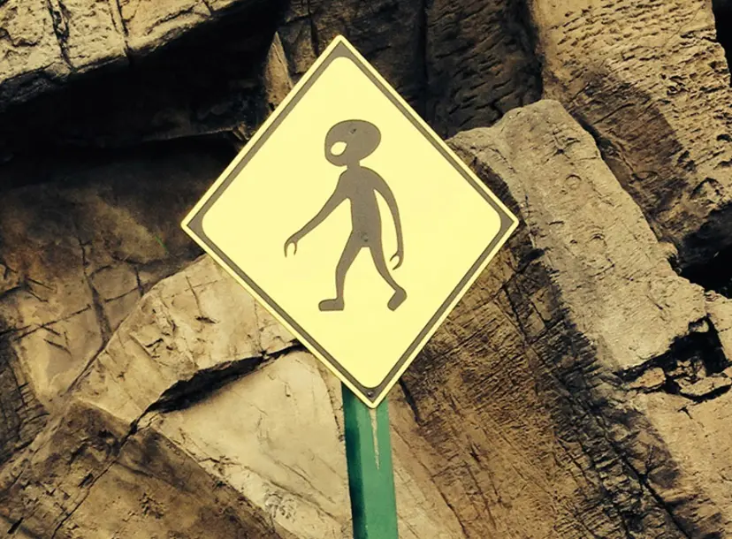 A diamond-shaped yellow sign with a silhouette of an alien walking