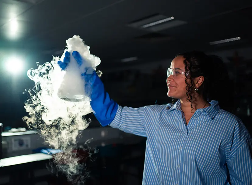 A woman holding a flask, its contents bubbling away in smoke