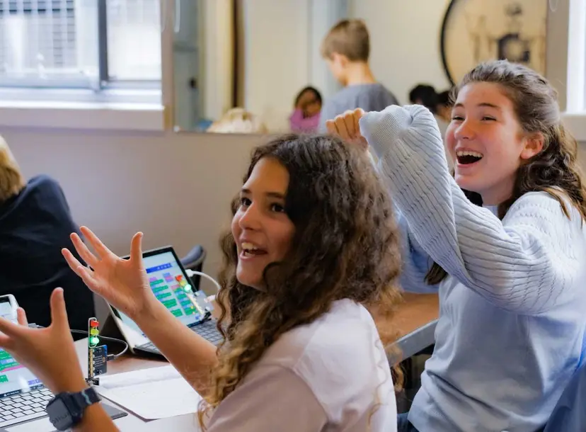 Two participants cheering as they are sat at laptops coding