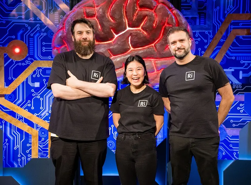 Three people in Ri t shirts stood in front of a large brain structure