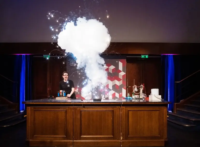 A person looks surprised as a eruption of sparks and smoke fills the air