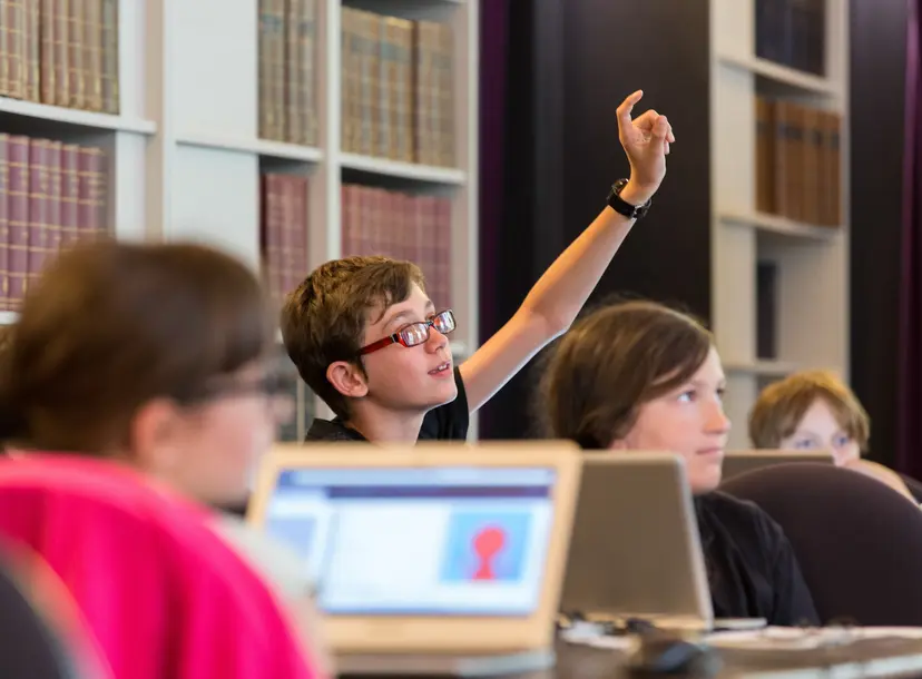 A child puts his hand up to ask a question during a coding workshop