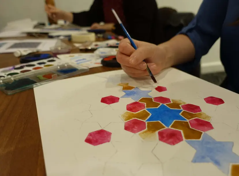 Image of someone painting some colourful geometric Islamic art they have drawn