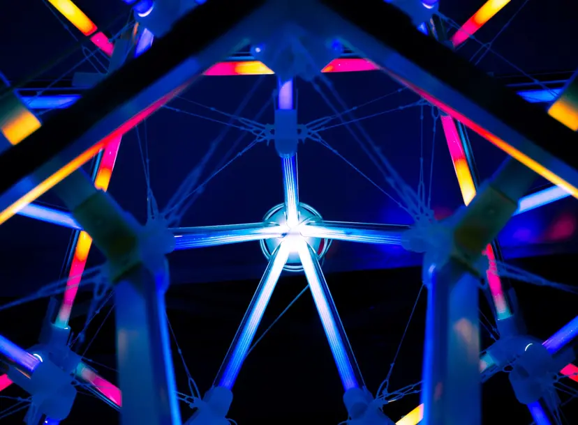 A designed image with lots of bright blue, pink and yellow lines. Some of them converge in the middle. 