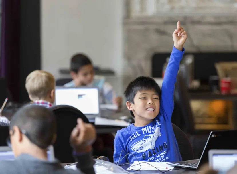 Child enthusiastically puts his hand up during a workshop 