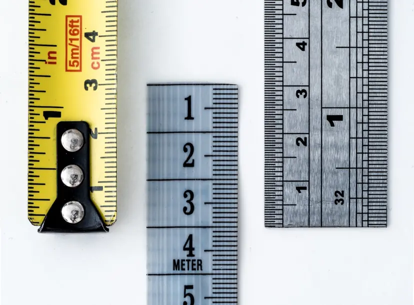 A close up of the end of a yellow tape measure, grey flexible measure and metal ruler.
