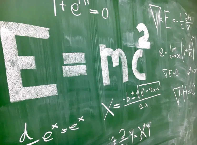 A green chalkboard has the equation 'E=c^2' written in large white letters. 