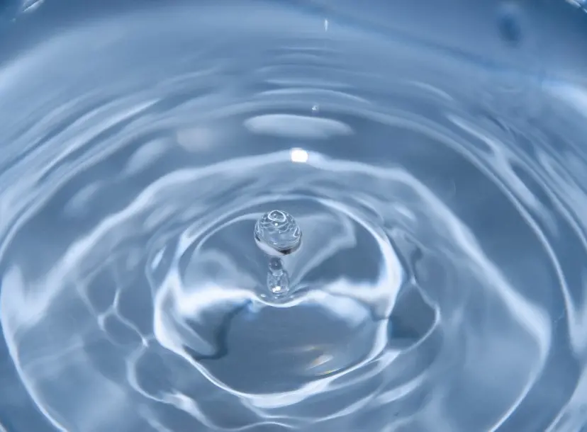a droplet of water bounces out of some water, creating ripples. 