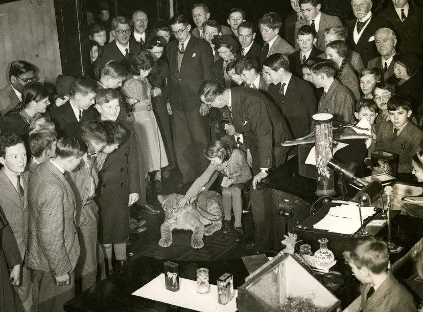 A black and white photo showing Julian Huxley surrounded by a crowd of people. It is part of his Christmas Lecture series from 1937.