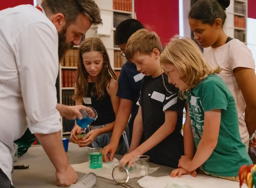 A man performing a science demonstration in front of five children