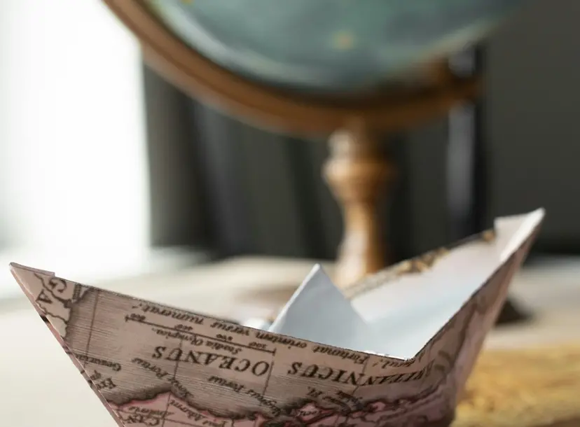 paper boat with globe in background