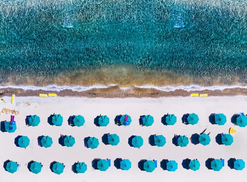 An aerial photo of umbrellas on a beach in a regular pattern