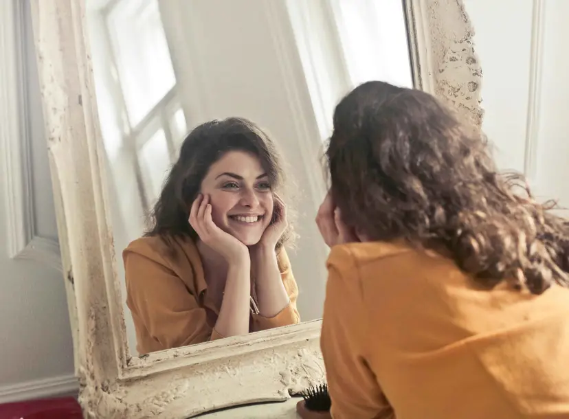 A women smiles into a mirror