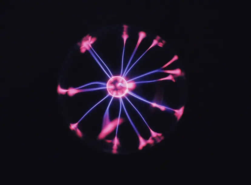 A plasma ball with a pink central ball of light and blue with blue sparks radiating out from it