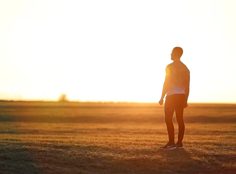 A man looks to the horizon on a meadow at golden hour