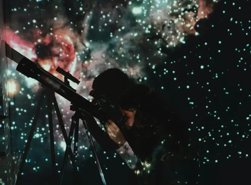 Child looks through a telescope surrounded by stars