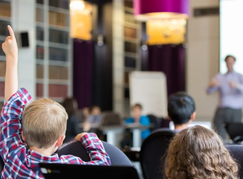 A child raising his hand in a classroom