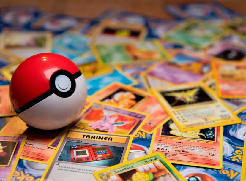 A red and white pokeball sits on top of lots of pokemon cards