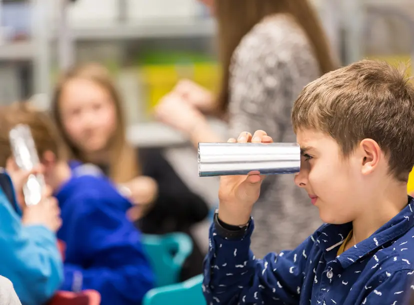 Participant holds a rolled piece of paper to their eye to look through
