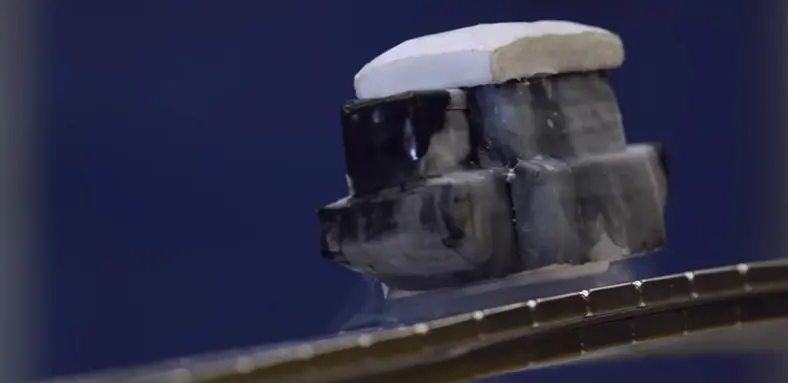 small metal box like object floating above a magnetised track