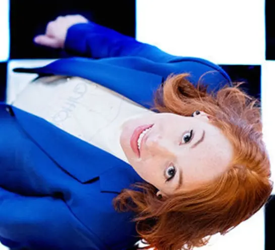 Hannah Fry in a blue suit looking up, standing in a chequered floor