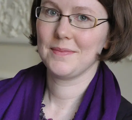 A picture of Harriet Wallace, a white woman wearing glasses and a purple scarf