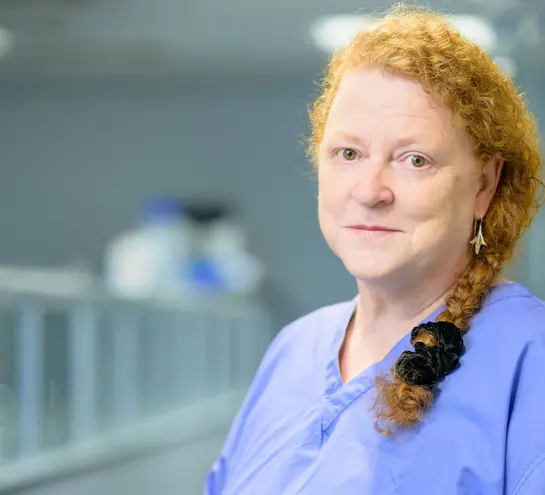 Sue Black, wearing scrubs, stands in a laboratory