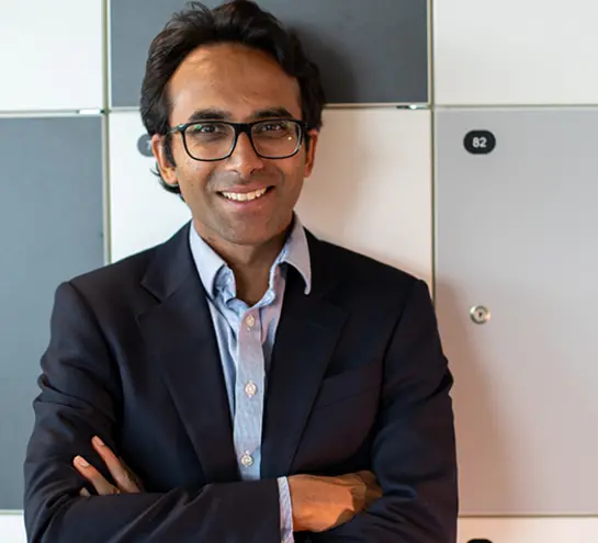 Ravi Gupta with his arms crossed, wearing a dark jacket and light shirt, smiling