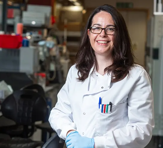 Teresa Lambe in a white lab coat and blue nitrile gloves in a lab