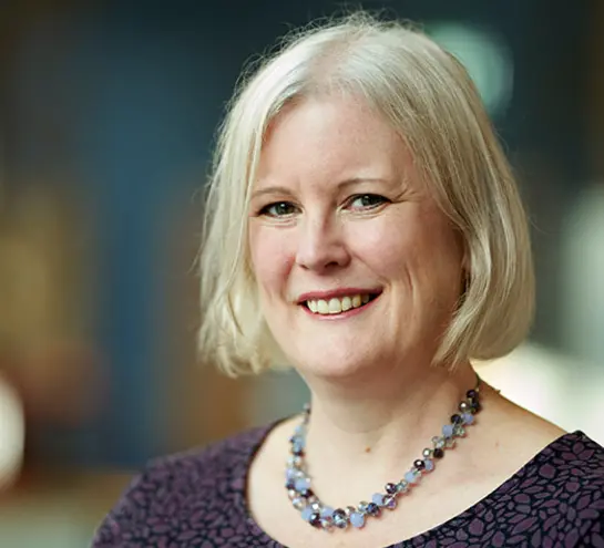 Catherine Noakes with a short blond bob haircut and a chunky necklace smiling