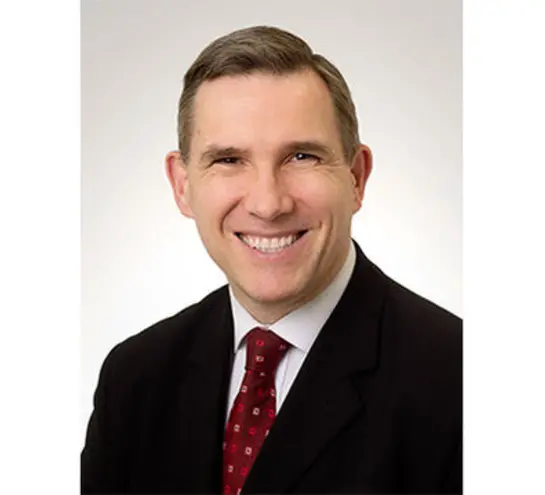 Chris Potter, he has short dar hair and is wearing a dark suit with a red spotted tie