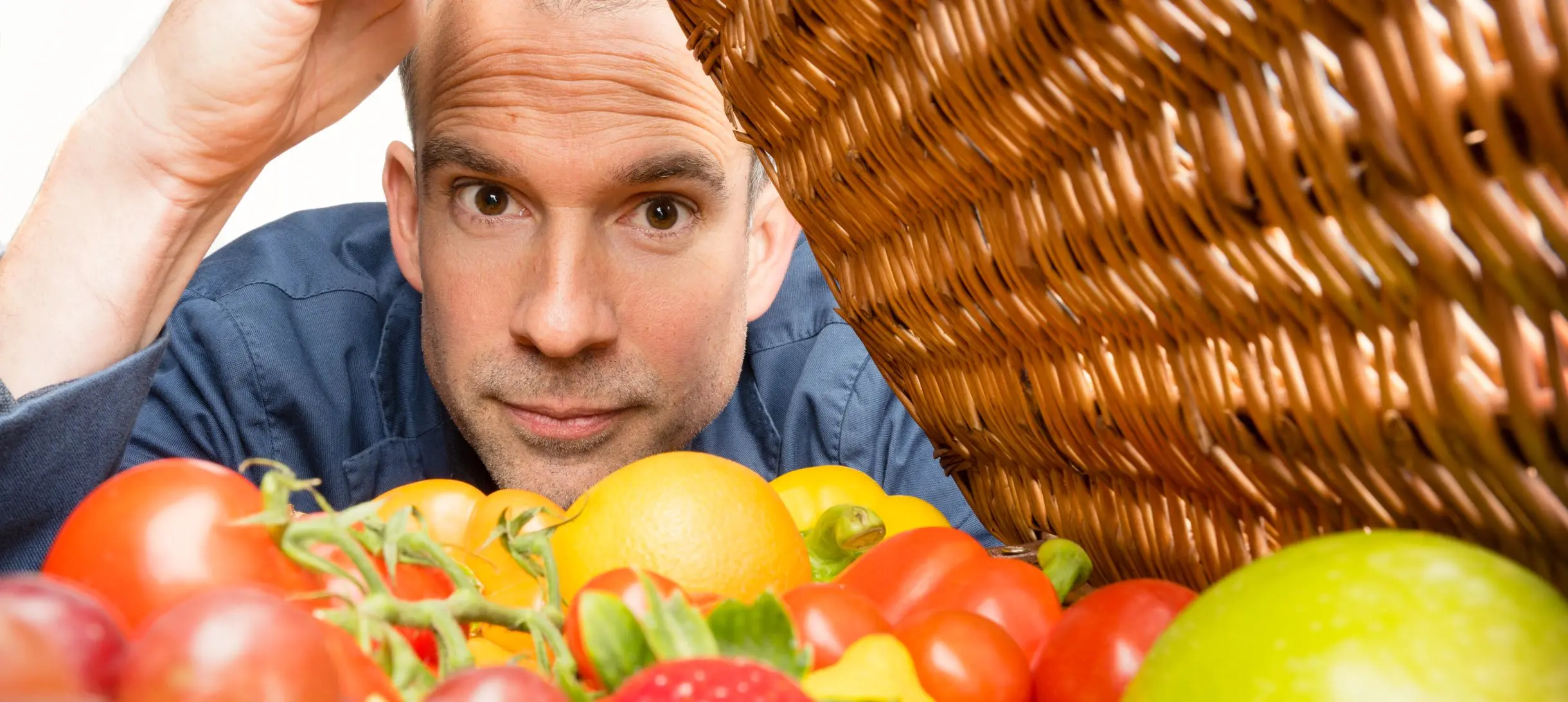 Chris peers into a basket containing fresh fruit and vegetables